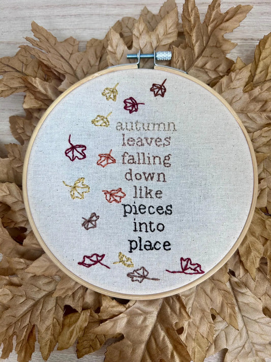 lyric from “All Too Well” by Taylor Swift embroidered on hoop on autumn leaves