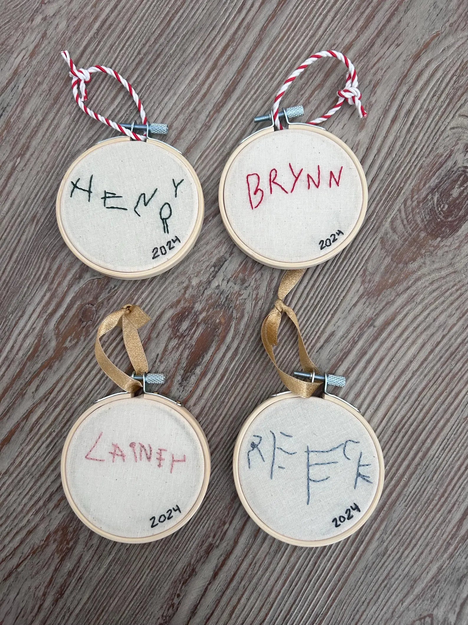 four children’s handwritten names custom embroidered ornaments on table